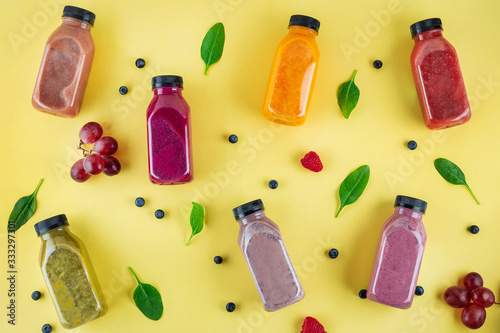 Colourful healthy smoothies and juices in bottles on color background with copy space.