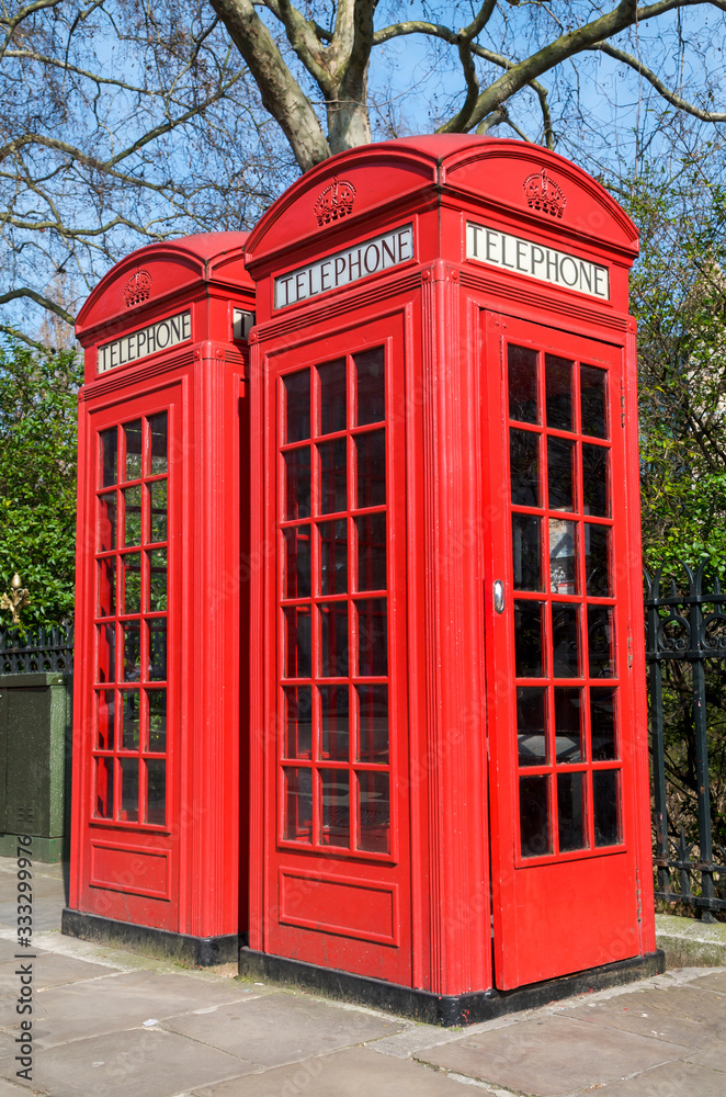 Pair of old-fashioned red British phone boxes standing on a spring sidewalk in London, UK Pair of old-fashioned red British phone boxes standing on a spring sidewalk in London, UK