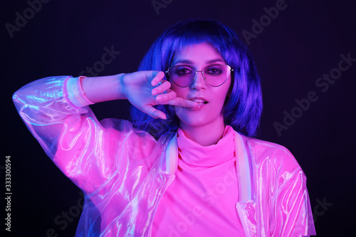 Neon light studio close-up portrait of happy woman model in a wig in sunglasses. Nightlife  party in a nightclub.