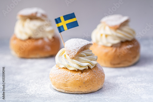 Traditional Scandinavian cream and almond paste filled cardamom bun Semlor with a Swedish flag. photo