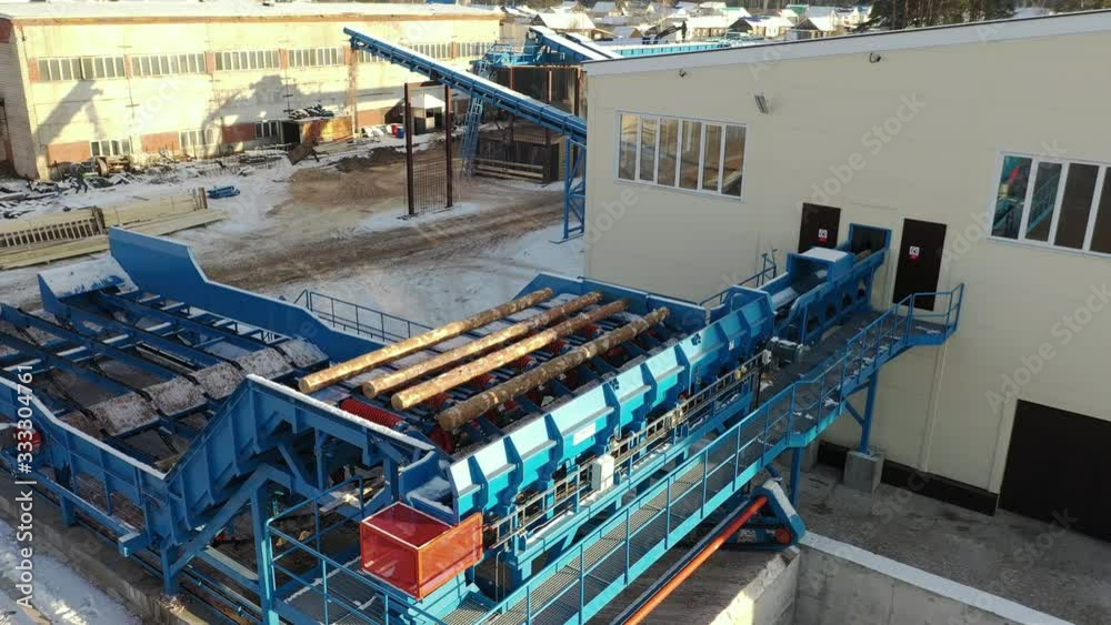 Aerial view of Automated log sorting line. Production of timber from wood. Woodworking. Machining logs. The logs in the sawmill are moving along a conveyor belt