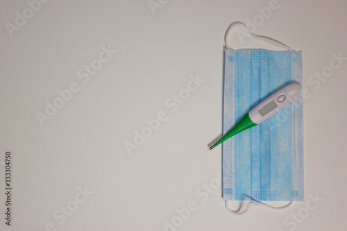 Medical masks and thermometer on white background with free space for text