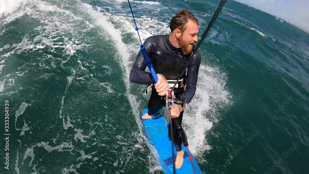 bearded man kitesurfing strapless in the waves