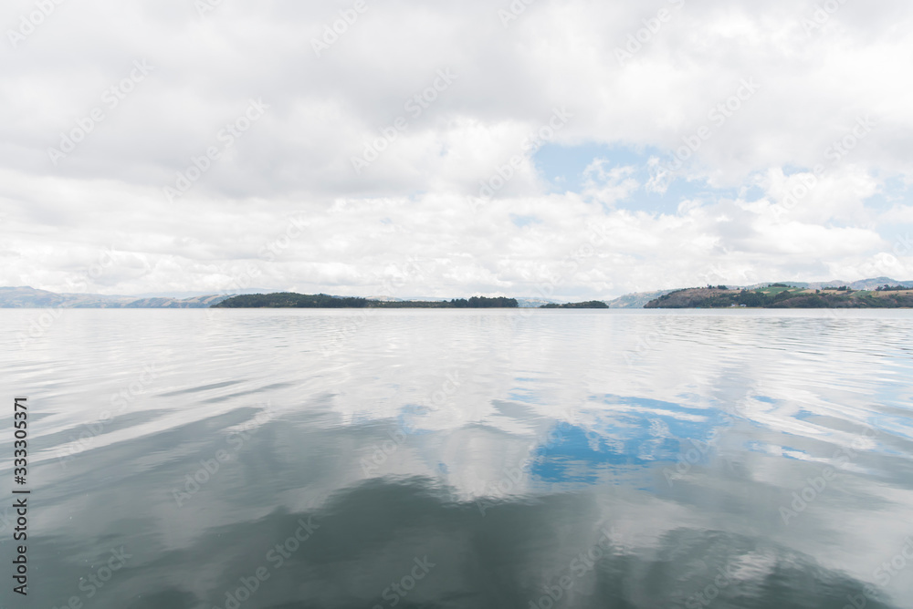 Tota lake, calm landscape, cloudy sky reflected in the water surface Tota lake, calm landscape, cloudy sky reflected in the water surface