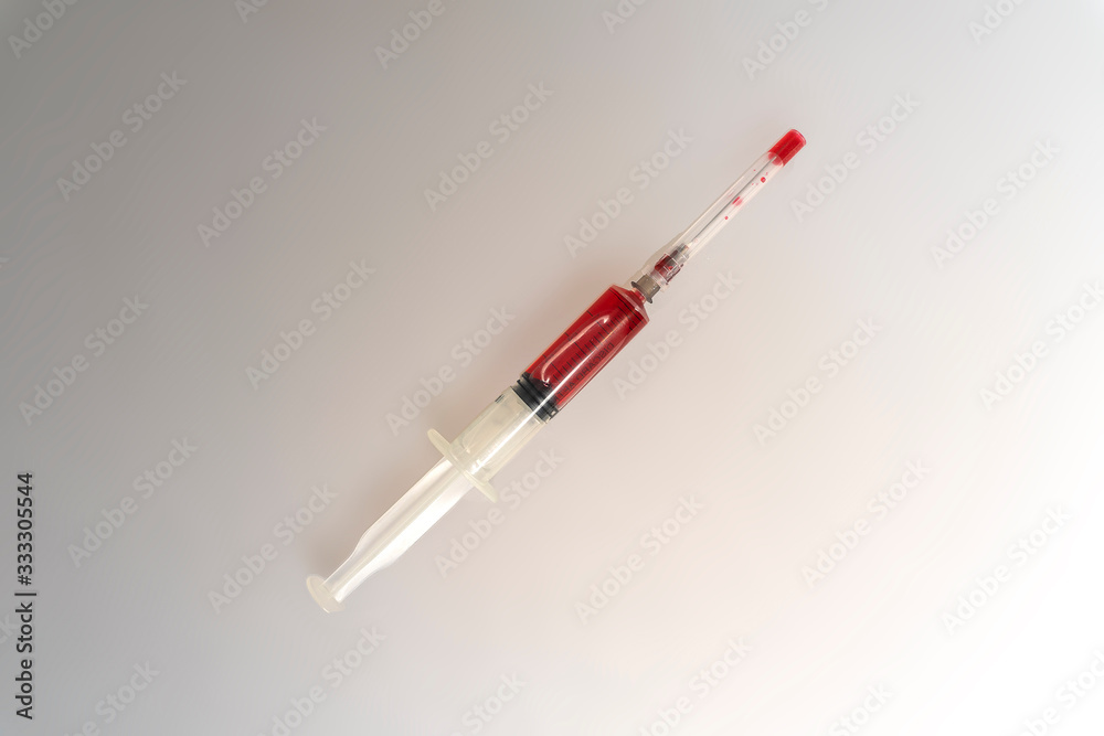syringe filled with red liquid on a light background syringe filled with red liquid on a light background