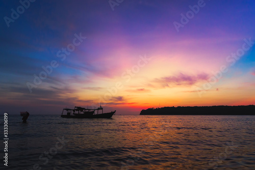 Amazing colorful sunset with fishing boat and fishing man in the water. trying to put all stuff on the boat.  © Tomas