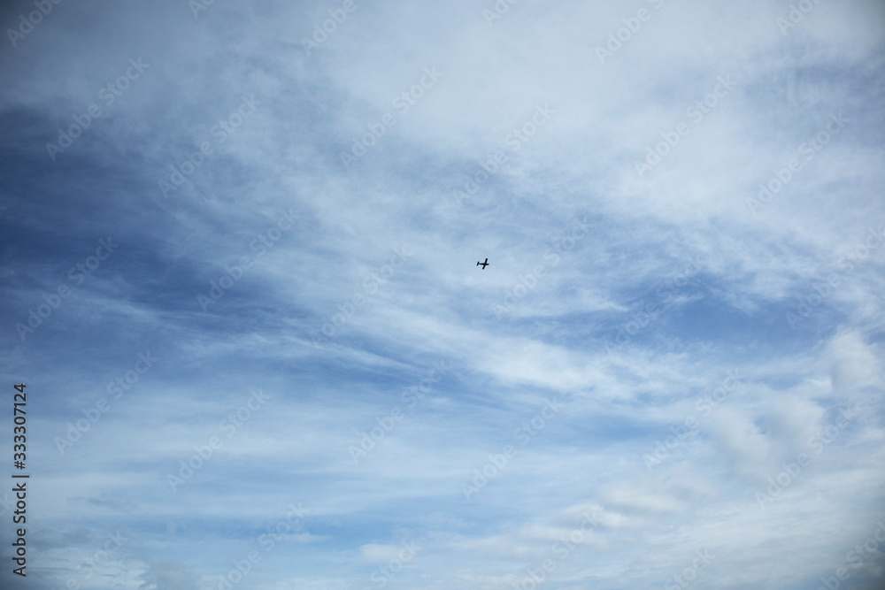 Clear blue sky, clouds and airplane silhouette, horizontal orientation Clear blue sky, clouds and airplane silhouette, horizontal orientation