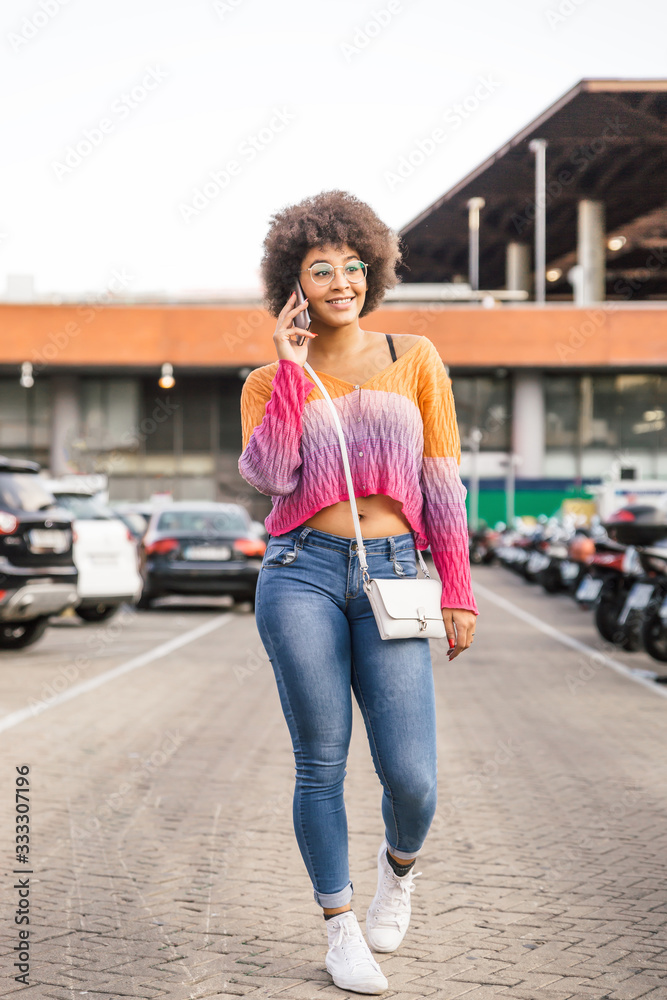 Beautiful girl with nice body dressed in casual spring clothes walks while  talking on her mobile phone Stock Photo | Adobe Stock