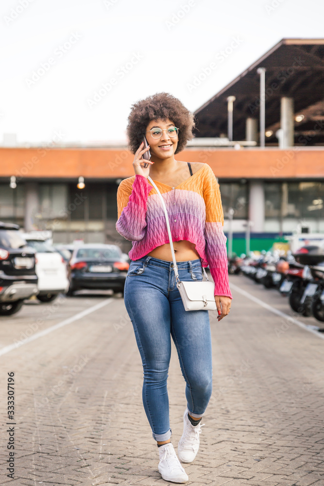 Beautiful girl with nice body dressed in casual spring clothes walks while talking on her mobile phone