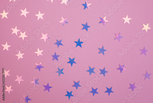 Pink and purple shiny star confetti over pink background.