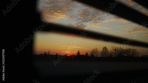 Watching the sunset through slits in the roller shutter and the clouds turn orange and red wide