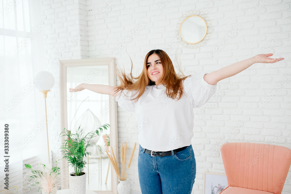 Happy plus size model in jeans and white t-shirt, tosses hair lifestyle.  Young plump woman in casual outfit. The body is positive. The concept of  one beauty. XXXL fashion Stock Photo