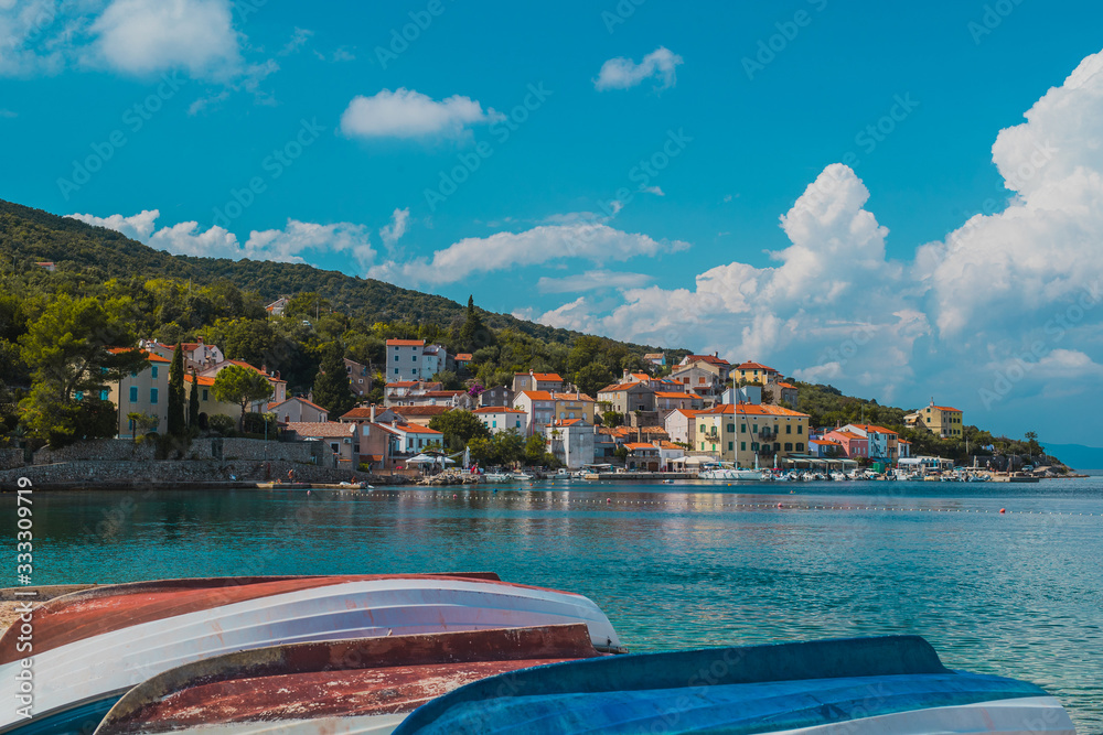 Postcard panorama of adriatic coastal city of Valun on Croatian island of Cres. Beautiful small picturesque village at the beach in the summer sun.  Boats in the foreground.