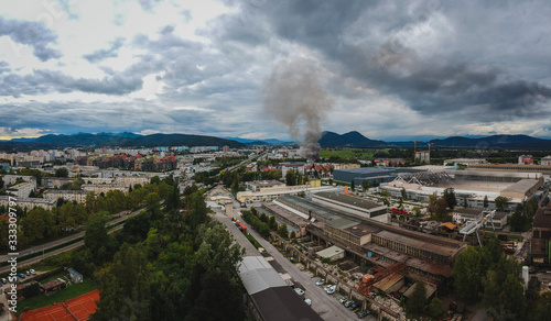 Aerial photo of a fire in industrial area of Stegne in Ljubljana, Slovenia. Dark plume of smoke is visble rising up from the place of ignition. Danger of pollution and respiratory problems for people. photo