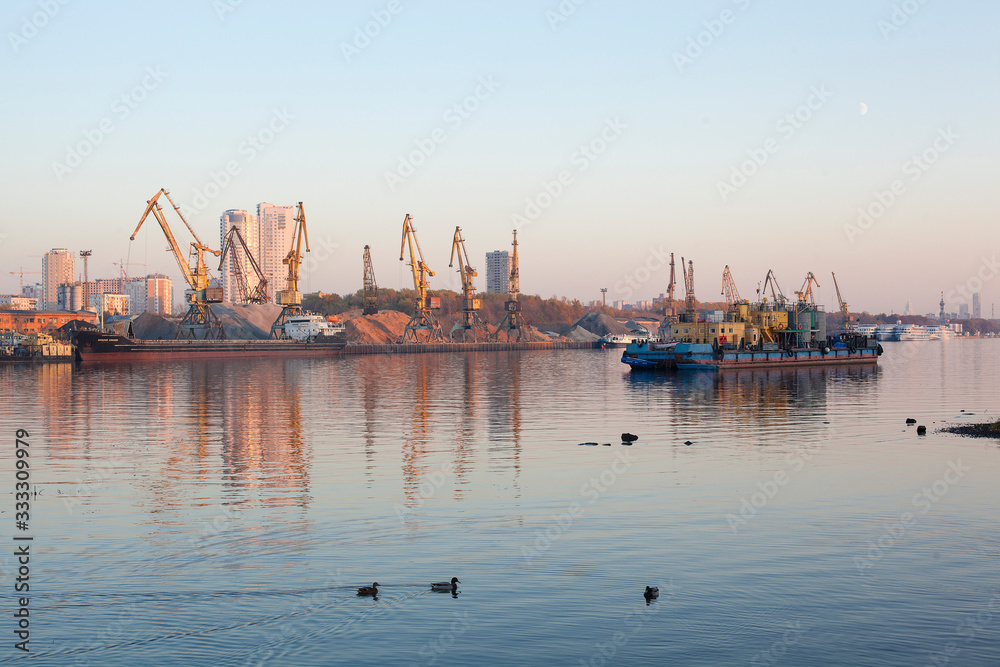 Barge and building cranes on river channel