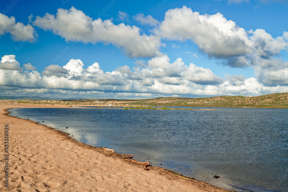 Sandy lakeshore with hills, and cloudy sky on background Sandy lakeshore with hills, and cloudy sky on background