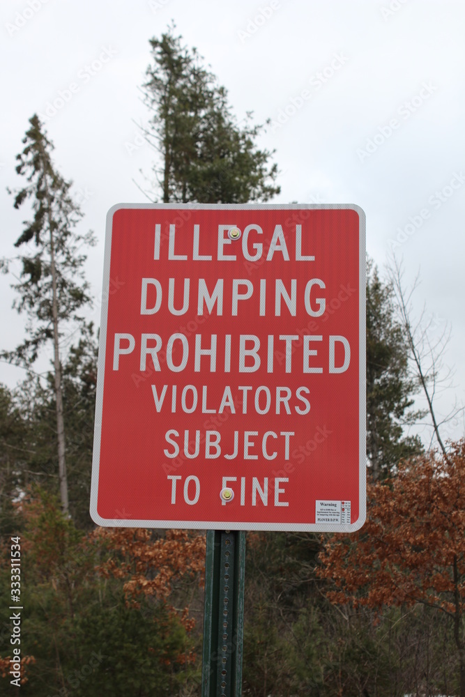 Illegal Dumping Sign in a park by trash dumpster