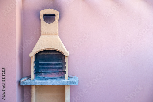 Traditional stone grill with pink wall in the background. Copy space