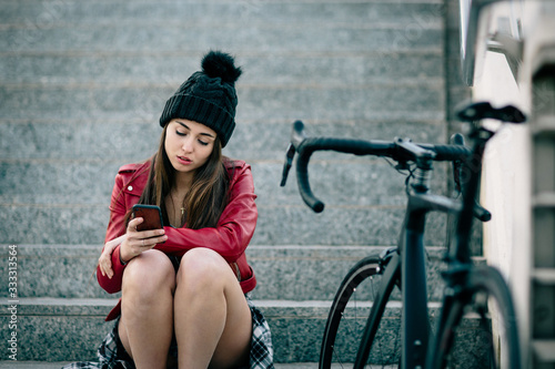 problem teenager sitting consulting his phone, travels with bicycle