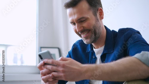 Happy man at home using smartphone