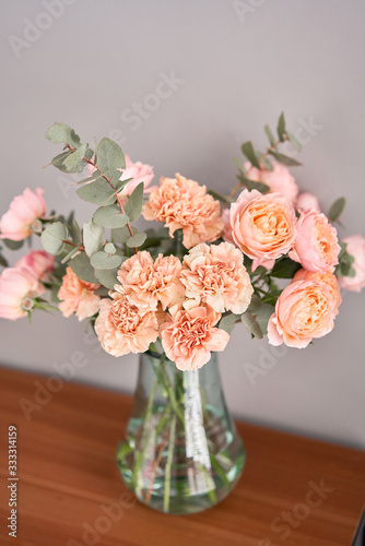 Flowers in glass vase on wooden table. Fresh cut flowers for decoration home. Delivery flower.