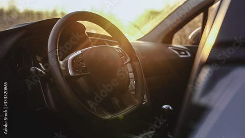 Interior view of car at sunset. Close up of steering wheel © glebcallfives