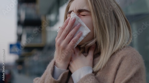 Sad young caucasian woman sneezing coughs feel sick outdoor fever cold allergy disease female nose sneeze lady runny tissue air pollution adult illness district coronavirus pandemic pneumonia covid19