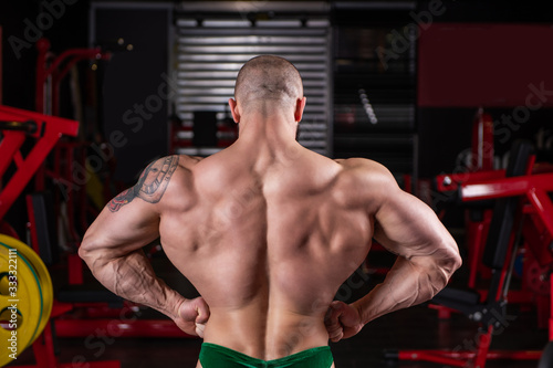 Fotografie Close up of powerful muscular man posing with muscle contraction at the gym