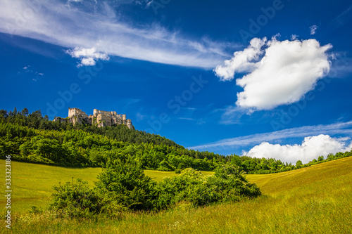 Bild auf Leinwand The ruins of a medieval castle Lietava on a rocky blade over a wooded landscape and grassy meadows, nearby Zilina town, Slovakia, Europe