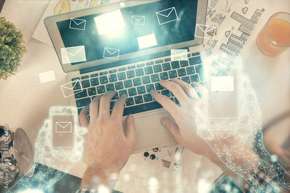 Double exposure of man's hands typing over computer keyboard and flying envelop hologram drawing. Top view. e-mail concept. Double exposure of man's hands typing over computer keyboard and flying envelop hologram drawing. Top view. e-mail concept.