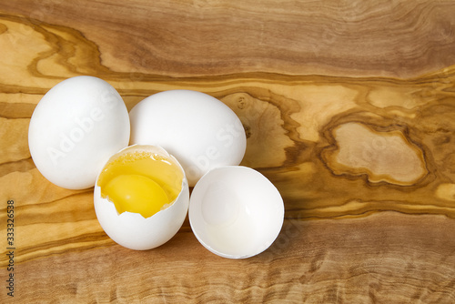 White chicken eggs and broken eggs on wooden board or table. close up