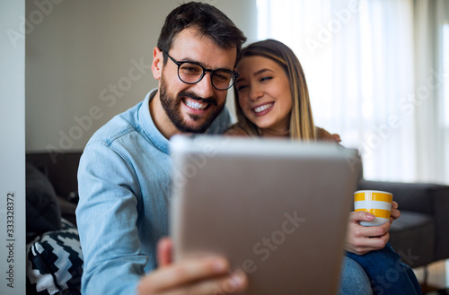Cheerful couple using tablet at his home
