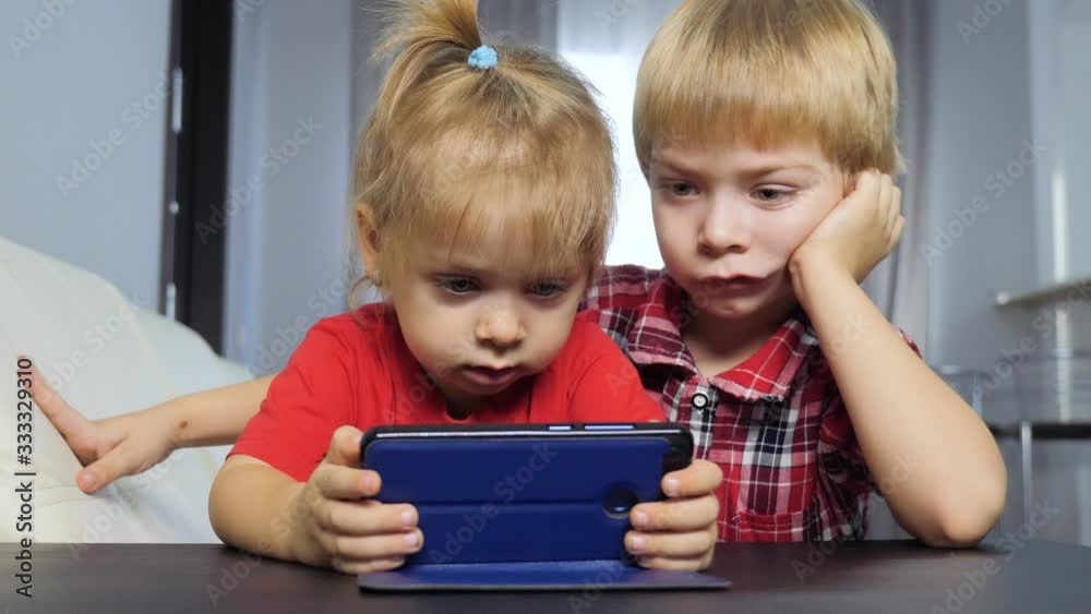 children watch online video on a smartphone. little boy and girl brother sister watch online streaming broadcasting lifestyle cartoons on the phone children watch online video on a smartphone. little boy and girl brother sister watch online streaming broadcasting lifestyle cartoons on the phone