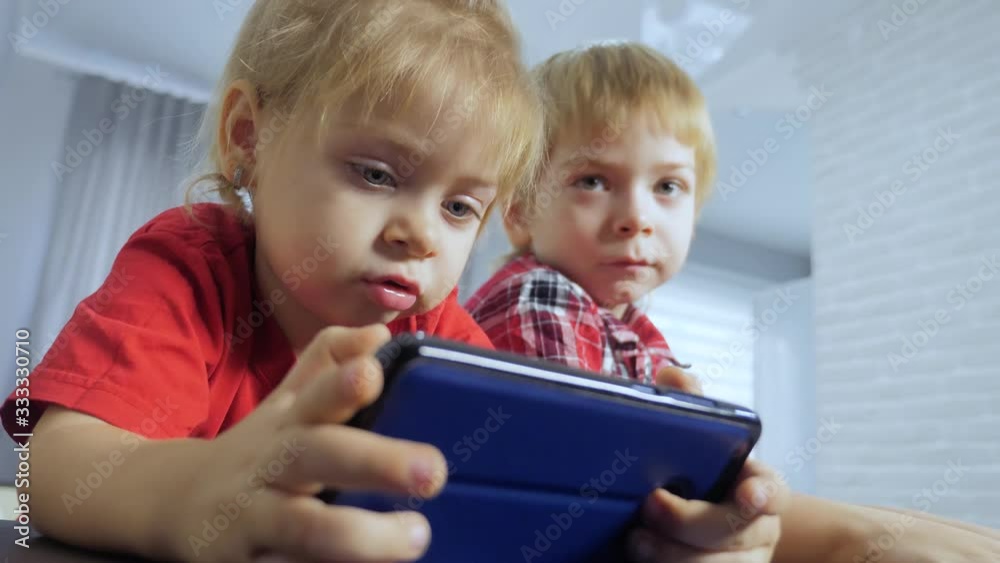 children watch online video cartoons on a smartphone. kids little boy and girl brother sister watch lifestyle online streaming broadcasting the phone children watch online video cartoons on a smartphone. kids little boy and girl brother sister watch lifestyle online streaming broadcasting the phone
