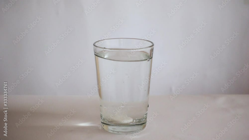 Medicinal tablet falling into a glass of water on a white background Medicinal tablet falling into a glass of water on a white background