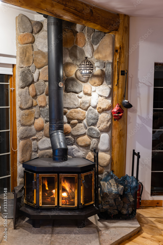 Wood stove fireplace with metal body and glass door in house with cozy  interior Stock Photo | Adobe Stock