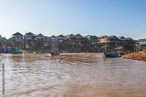 Kampong Phluk Floating Village on Tonle Sap lake near Siem Reap, Cambodia during sunset. The Stilt houses of the floating town. Exotic places South East Asia. Boats cruising around and selling goods