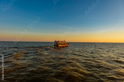 Sunset at Tonle Sap Lake, Cambodia, near the Kampong Phluk Floating Village and Siem Reap. Tourism boats cruising on the water to enjoy the breathtaking colorful sunset. Sunset horizon over the sea. © Holger