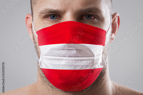 Photography Young man with sore eyes in a medical mask painted in the colors of the national flag of Austria