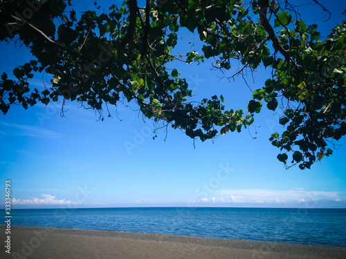 Fototapeta Naklejka Na Ścianę i Meble -  Tropical Beach Scenery Under The Shade Tree On Sunny Clear Blue Sky At The Village, Umeanyar, North Bali, Indonesia