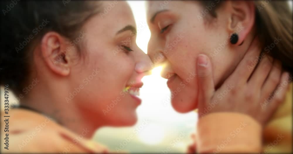 Women kissing passionately in the sunlight lens-flare. LGBT lesbian kiss