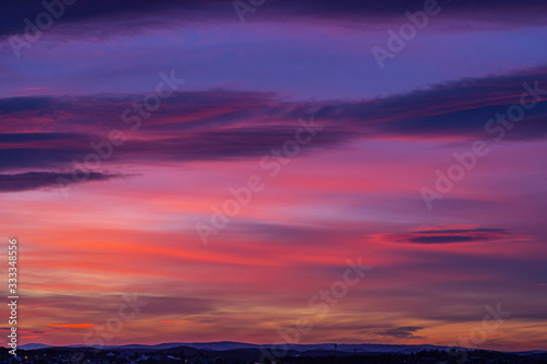Bright red-blue-orange sunset in the sky with clouds. Beautiful colorful dawn above the earth. Artistically blurry.