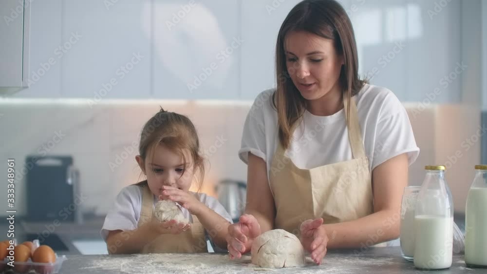 Mother and daughter cooking with dough mold in kitchen. Mother and daughter holding heart-shaped dough mold. Sculpt the dough with your hands to make blanks for pizza or pie, cookies Mother and daughter cooking with dough mold in kitchen. Mother and daughter holding heart-shaped dough mold. Sculpt the dough with your hands to make blanks for pizza or pie, cookies