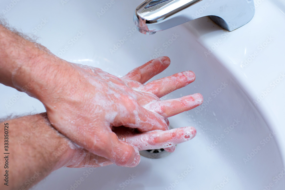 Fototapeta premium A Man is washing his hands with soap in bathroom.