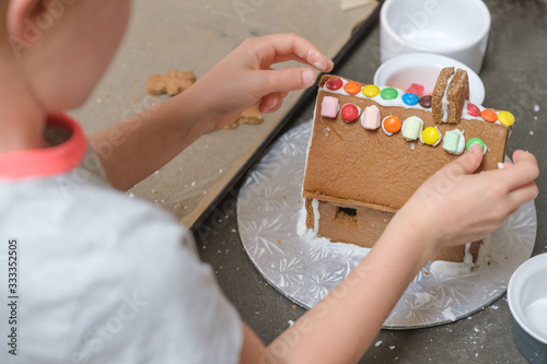 girl putting finishing touches to gingerbread house