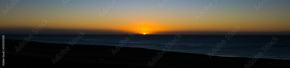The last rays of a setting sun as it falls below the ocean horizon