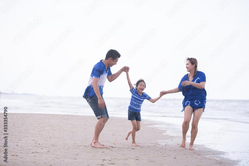 Asian family wear blue tone outfit playing and have a happy time on the beach. Family good relationship concept