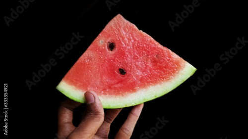 The man holding the watermelon with slices isolated on black background