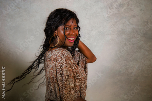 young stylish and happy black African American woman posing confident and playful isolated on grunge background looking at camera in cool and positive attitude smiling cheerful