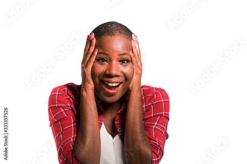 young beautiful and cool black African American woman in casual shirt and shaved hair excited and surprised isolated on dark background in wow face expression